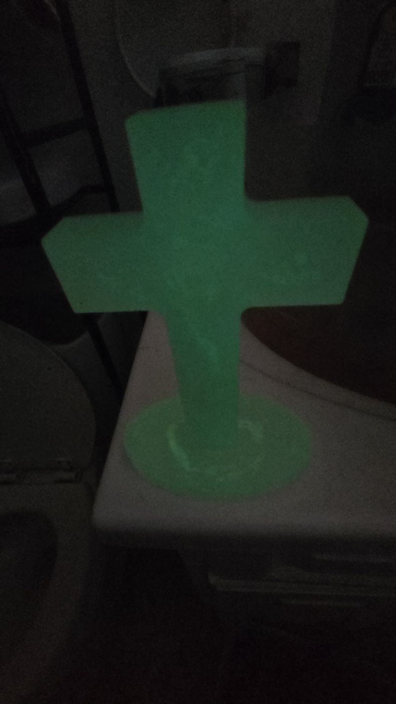 Glow-in-the-dark cross glowing green at night