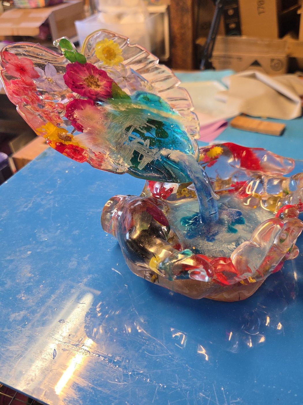 Resin cupped hands catching a leaf pour filled with pressed flowers